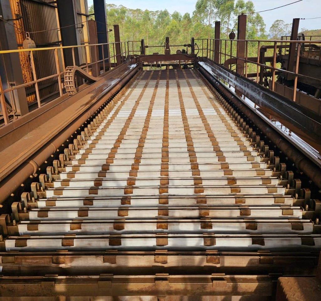 | Micronics Engineered Filtration Group Industrielle Rollenbahn in einer Fabrik, die sich in Richtung einer entfernten Plattform mit Sicherheitsgeländern erstreckt.